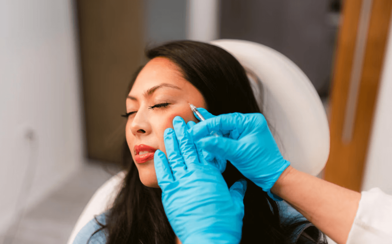 Woman receiving facial cosmetic injections from a practitioner in gloves.