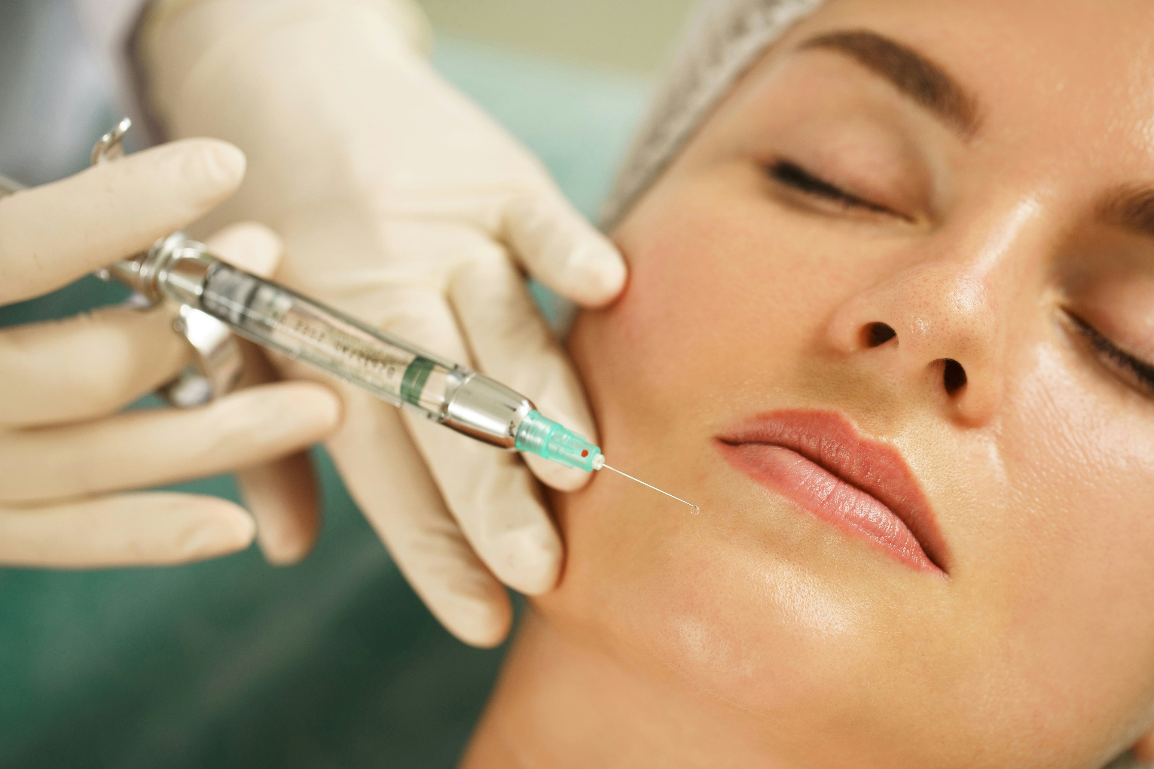 Woman receiving a cosmetic facial injection treatment from a practitioner wearing gloves.